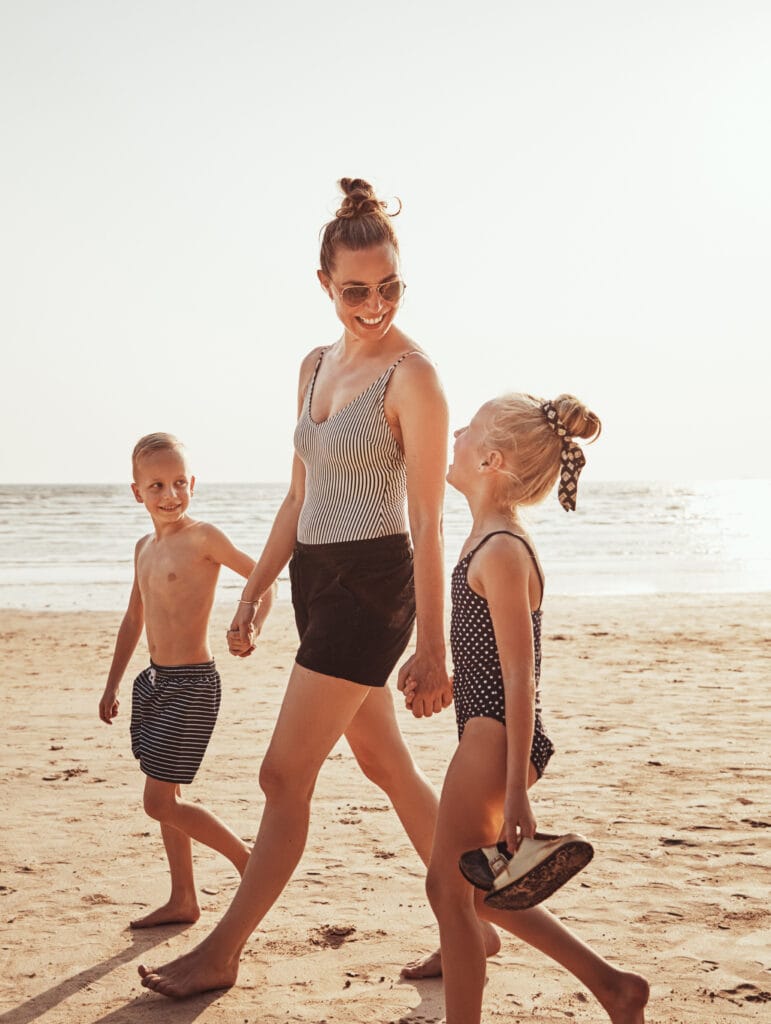 Smiling Mom and her kids walking along a sandy beach